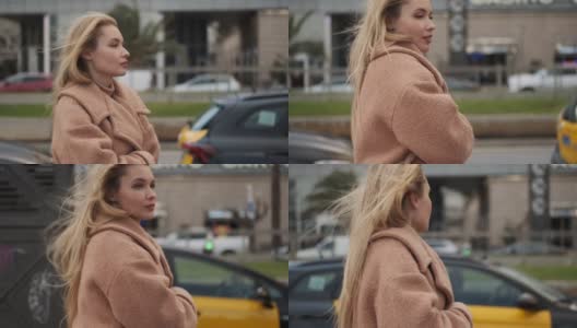 美丽浪漫的金发女孩，穿着时髦的外套，梦幻般的走在出租车停车场在城市街道高清在线视频素材下载