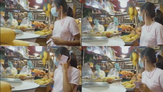 在泰国著名海鲜店华欣夜市买芒果糯米饭的亚洲孩子们戴着口罩。高清在线视频素材下载