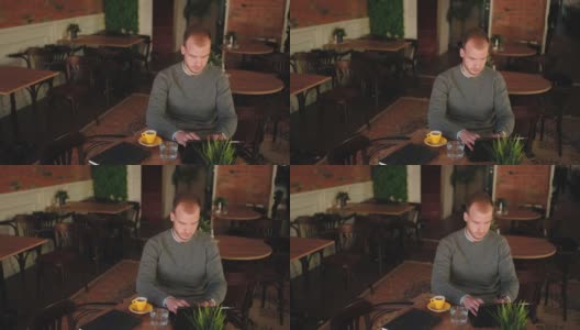 专注的男性自由职业者在餐厅里摆弄他的Ipad高清在线视频素材下载