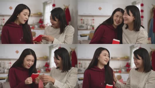 春节在家收红包时，身着红色衣服的亚洲女儿微笑着拥抱母亲的特写高清在线视频素材下载
