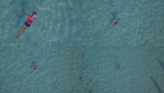 鸟瞰图，一个迷人的女人漂浮在水晶清澈的大海，泰国，萨顿高清在线视频素材下载
