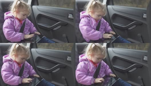 小女孩暖和衣服，在车上玩平板电脑高清在线视频素材下载