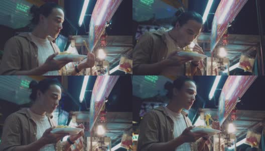 一名年轻的亚洲男子在店里吃泰式炒面高清在线视频素材下载