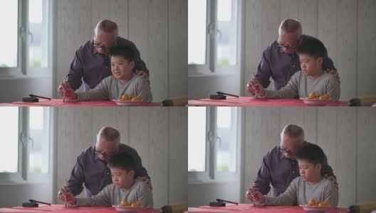 亚洲华人小男孩向他的祖父学习写中国书法高清在线视频素材下载