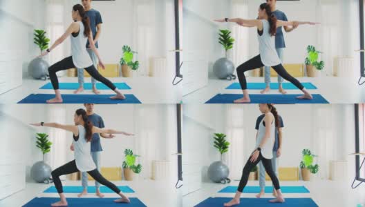 亚洲年轻情侣夫妇玩瑜伽和一起锻炼在家里的背景。锻炼身体，增加柔韧性，收紧体型。4 k慢动作。高清在线视频素材下载
