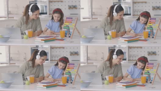 母亲在家里用笔记本电脑工作，而女儿在旁边的学校学习高清在线视频素材下载