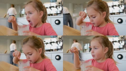 女孩在吃冰淇淋，妈妈在厨房清理台面高清在线视频素材下载