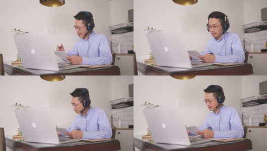 亚洲华人中年男子正在厨房里上网络课，早上还在用笔记本电脑高清在线视频素材下载