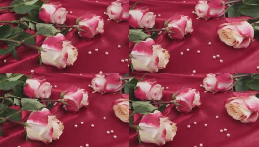 粉红色的珍珠落在深红色的缎子和粉红色的玫瑰上高清在线视频素材下载