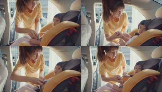 快乐快乐的亚洲家庭妈妈和蹒跚学步的女孩在车里准备出行前系好儿童汽车座椅安全带。高清在线视频素材下载