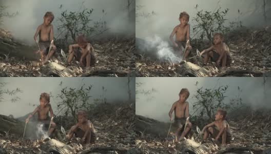 快乐的亚洲男孩坐在篝火前烤鱼与快乐的情绪。高清在线视频素材下载