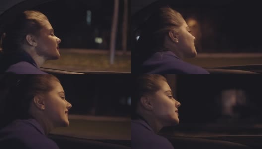 从车里看:美丽的年轻女子从车窗里探出身子，看着夜晚的城市。Slowmotion拍摄高清在线视频素材下载
