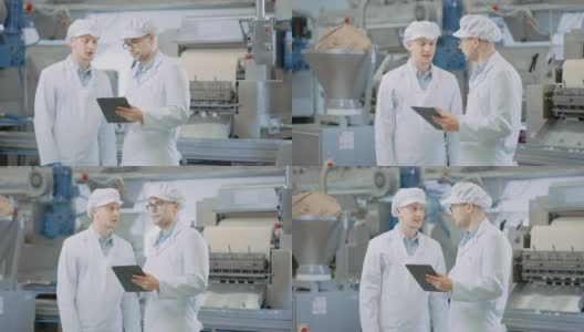 两个年轻的食品工厂员工讨论与工作有关的事情。男性技术员或质量经理使用平板电脑工作。他们戴着白色的卫生帽和工作袍。高清在线视频素材下载