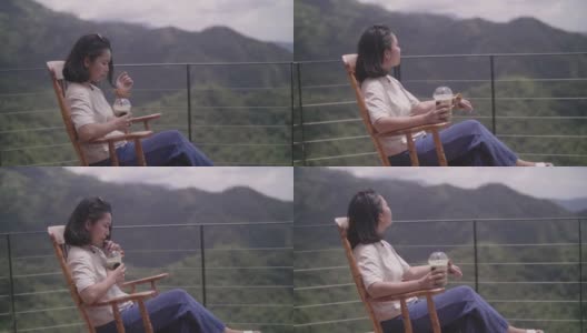 年轻女子坐在摇椅上喝茶。高清在线视频素材下载