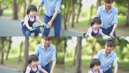亚洲小女孩学习骑自行车与年轻的母亲在花园高清在线视频素材下载