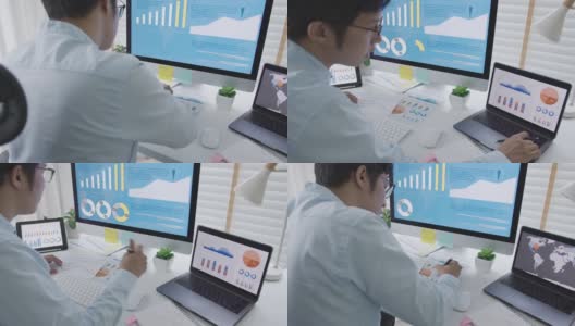 越过头肩后的年轻有吸引力的亚洲泰国男子忙于工作的多屏幕电脑或智能平板电脑在家里的桌子上的自由职业者数据分析师，数据科学的企业科学家。高清在线视频素材下载