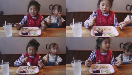两个亚洲小孩在餐厅吃饭。高清在线视频素材下载