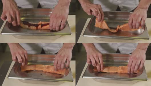 一个厨师的手的特写镜头，一个男人正在烹饪一块鳟鱼在一家餐馆高清在线视频素材下载