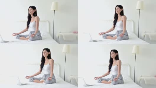 美丽的年轻女子在白色房间的床上练习瑜伽高清在线视频素材下载