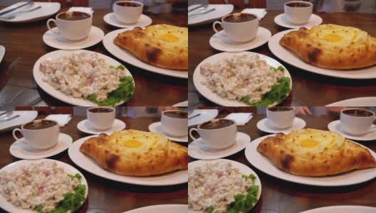 格鲁吉亚餐厅里的阿贾利安·哈切布里(Adjarian Khachapuri)，旁边是沙拉、煎蛋卷和咖啡高清在线视频素材下载