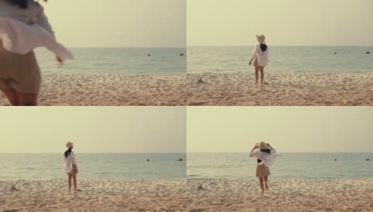 快乐的亚洲女人跑到海滩与手臂举起惊人的美丽的海洋沙的日落。高清在线视频素材下载