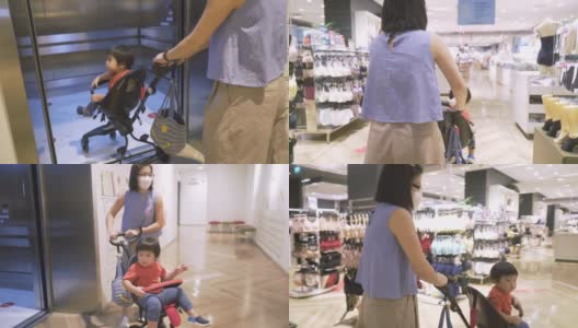 亚洲母亲戴着防护口罩，儿子坐在购物中心的婴儿车在假日季节高清在线视频素材下载