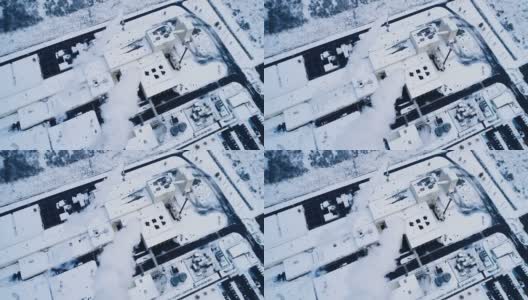 一架无人机俯瞰积雪下的工厂。我们可以看到烟从烟囱里冒出来高清在线视频素材下载