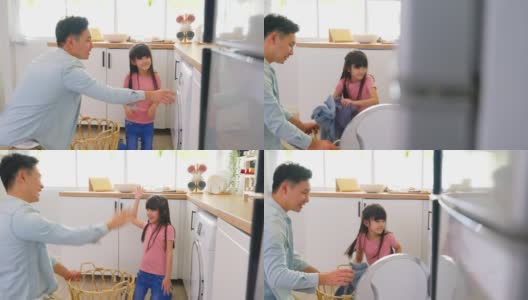 亚喜一家人呆在家里，爸爸教女儿洗脏衣服。小可爱的小女孩帮助和学习父母爸爸把衣服放在洗衣机电器在家里。Domestic-Housekeeping。高清在线视频素材下载