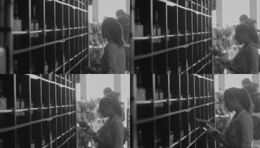一张黑白照片，一个女人从酒类商店的柜台上拿起一瓶葡萄酒高清在线视频素材下载