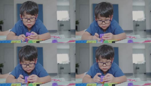 人像吸引人的聪明可爱的快乐的亚洲小男孩戴着眼镜享受在客厅玩五颜六色的高楼高清在线视频素材下载