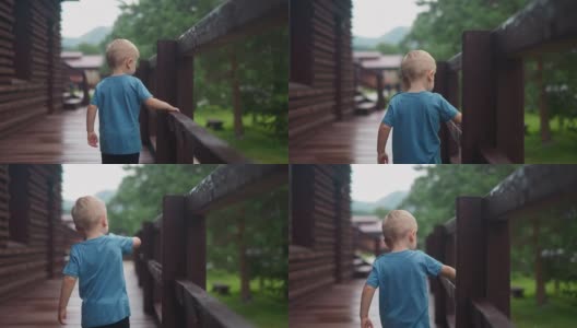 好奇的小男孩摸了摸甲板上潮湿的木栏杆高清在线视频素材下载