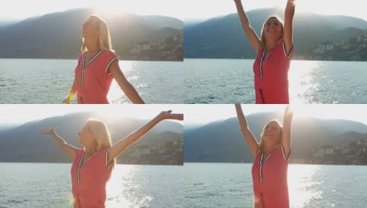 日落时分，在湖边，欢呼的妇女举起了她们的手臂高清在线视频素材下载