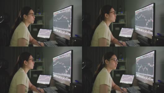 女性在家庭办公室看着电脑屏幕上的股票市场数据，同时与电脑工作高清在线视频素材下载