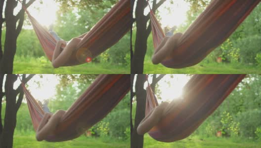 一个年轻女子在树下的吊床上休息高清在线视频素材下载