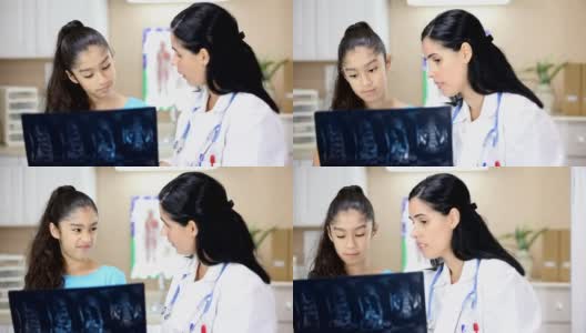 拉丁女医生拿着病人的x光片。她正在给年轻的拉丁女病人做体育检查。高清在线视频素材下载