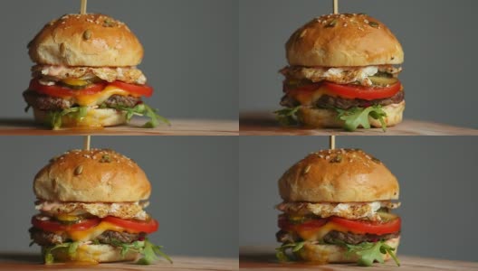 大汉堡配牛肉片，番茄，蘑菇，黄瓜和融化的奶酪在木板上旋转，背景光线高清在线视频素材下载