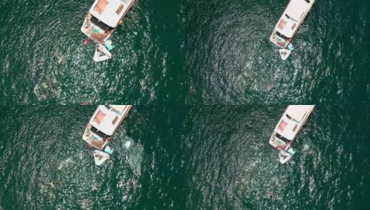 一艘抛锚的游艇和从四轴飞行器上看到的在太阳耀斑中游泳的人们高清在线视频素材下载