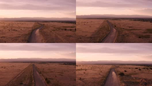 新墨西哥沙漠公路的乡村景象:夕阳下，汽车行驶在一条土路上高清在线视频素材下载