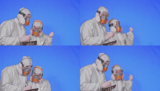 科学家病毒学家在呼吸器上用手写笔在平板电脑上写字。一男一女戴着医用防护口罩。色度键蓝色。高清在线视频素材下载