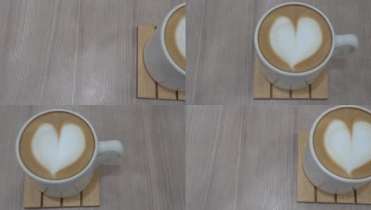 餐馆的木桌上放着一杯咖啡。拉花的形状是心形的。卡车从左向右飞驰。在看。高清在线视频素材下载