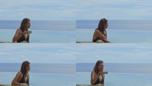 一名年轻女子的肖像正在度假泳池边喝咖啡边看海高清在线视频素材下载