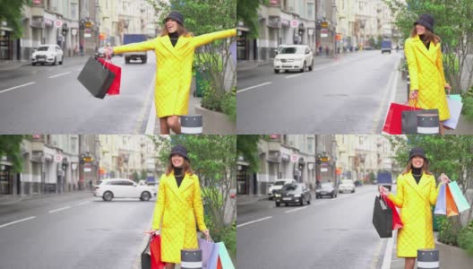 在购物中心附近的大街上，一个带着购物袋的快乐时尚女人正试图拦一辆出租车。快乐的生活方式和假日折扣的概念。高清在线视频素材下载