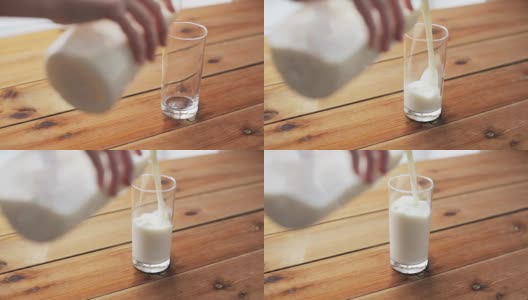 用手把牛奶倒进木桌上的玻璃杯里高清在线视频素材下载