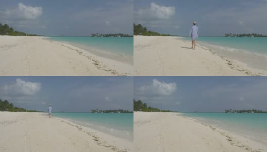 一个穿着衬衫和帽子的年轻女孩沿着海边的白色沙滩走着。马尔代夫高清在线视频素材下载