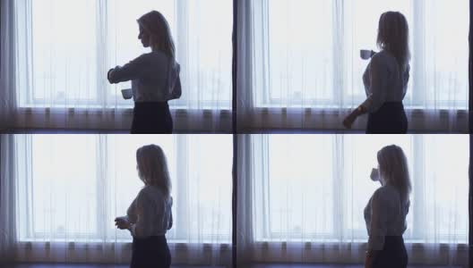 一位优雅的女孩站在窗边喝咖啡高清在线视频素材下载