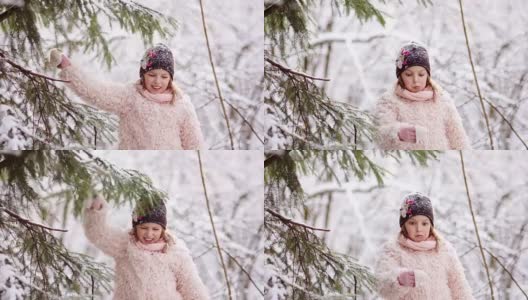 这个女孩在森林里摇掉树枝上的雪。快乐的童年。冬天的乐趣高清在线视频素材下载