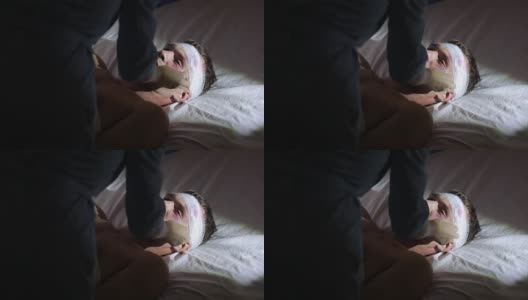 一个头部受伤的人躺在床上。护士照顾一个受伤的人高清在线视频素材下载