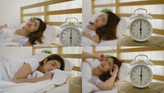 年轻美丽的亚洲女人在自己的床上醒来，闹钟叫醒的概念高清在线视频素材下载