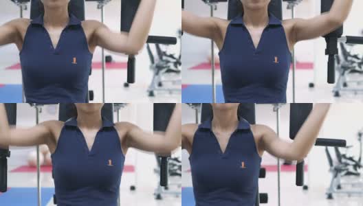 年轻的健身女士在体育馆里用力量锻炼机锻炼肌肉高清在线视频素材下载