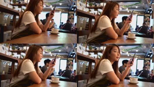 一个亚洲女人在周末的咖啡厅使用手机时对着镜头微笑高清在线视频素材下载